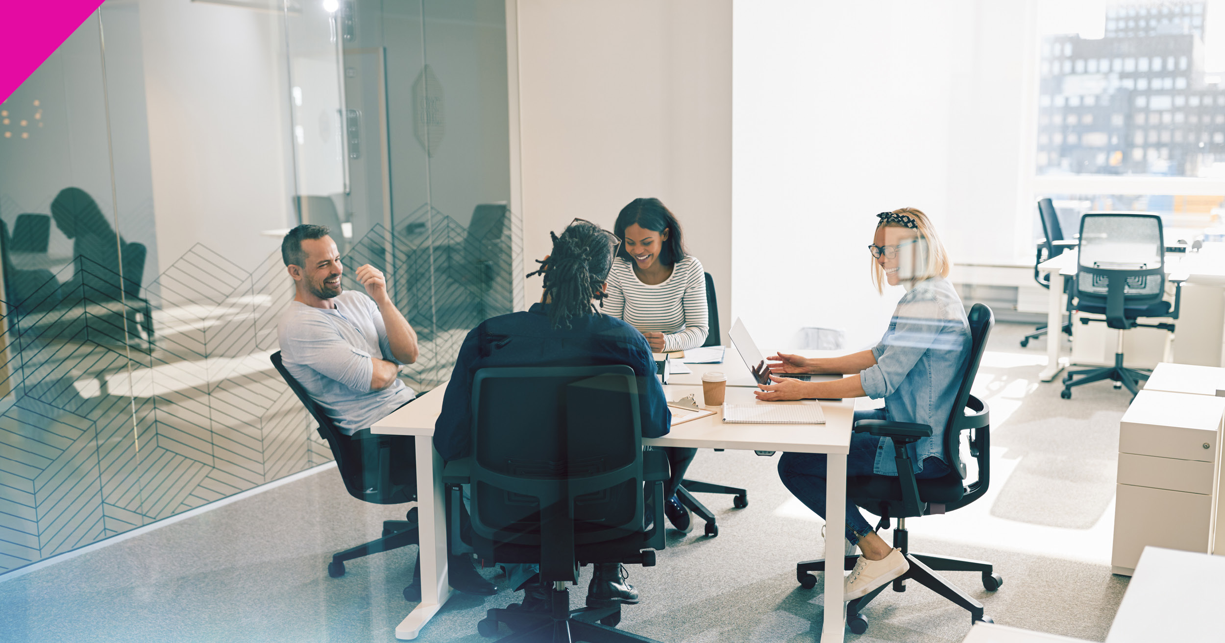 Four people sat around a desk smiling