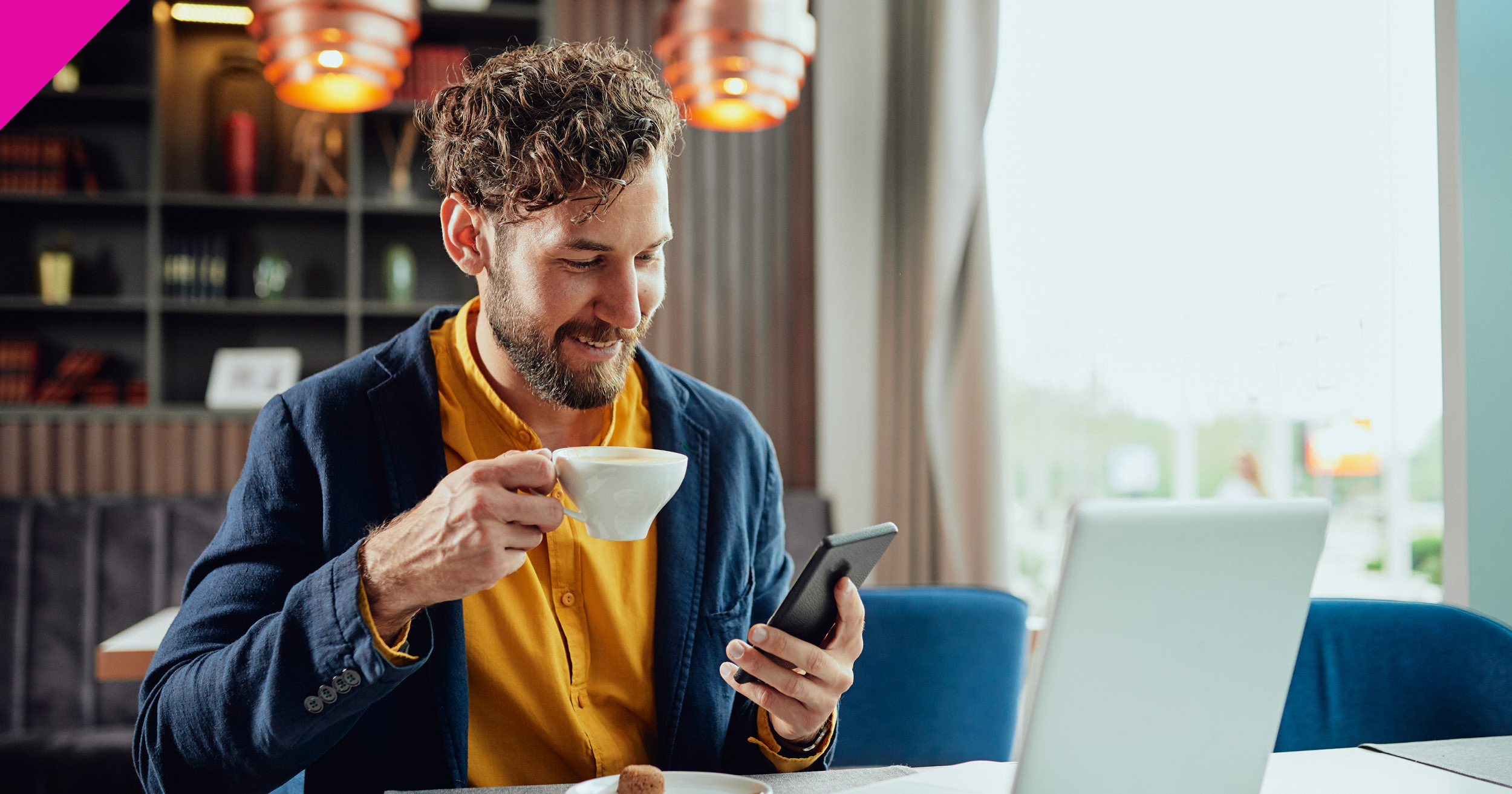 Man sat at computer looking at phone 