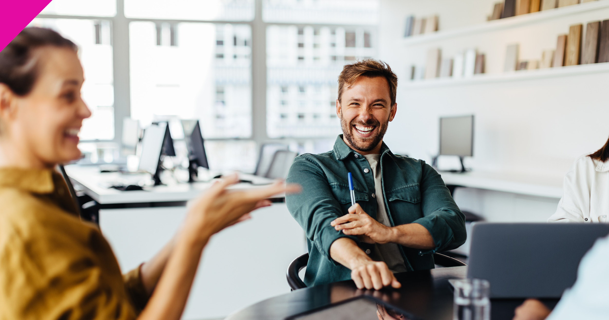 Man smiling sat at meeting table with laptop